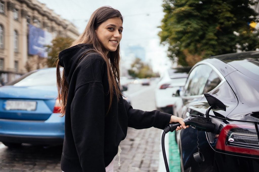 mulher recarregando carro elétrico