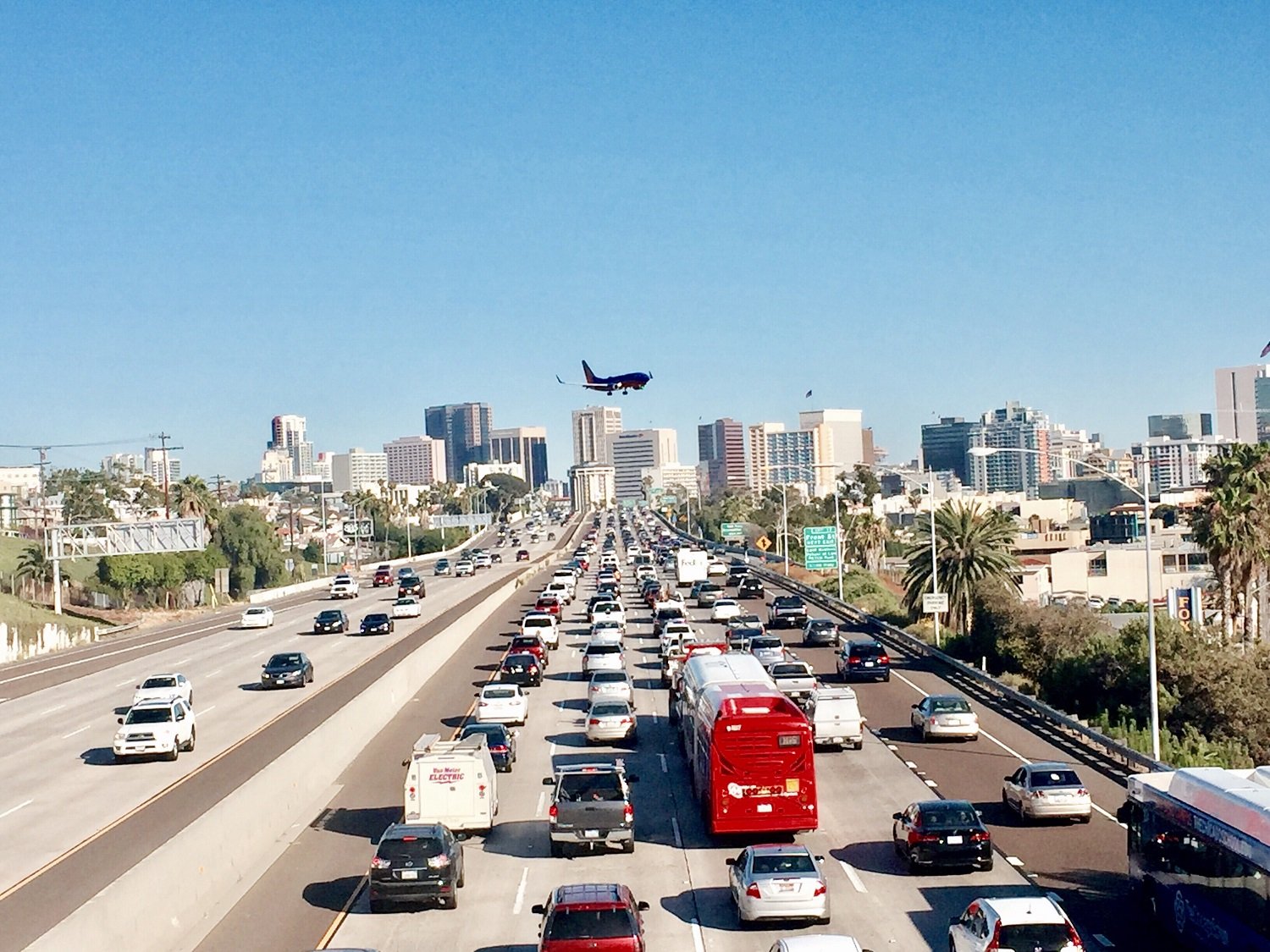 imagem de uma rodovia nos Estados Unidos. Vários carros ocupam as três faixas da pista e ao fundo é possível ver um avião decolando. Todas estas são causas de poluição sonora